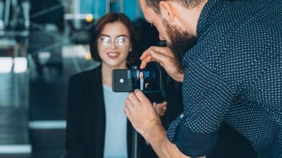 man adjusting camera while woman sits ready to be interviewed