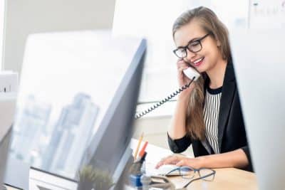 friendly young woman answering the phone at her desk