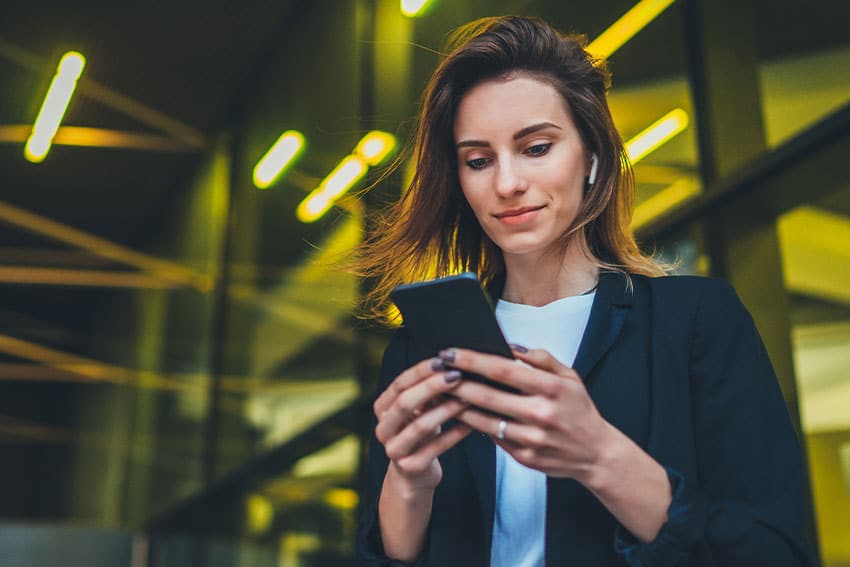 attractive business woman checking her cell phone outside her office 