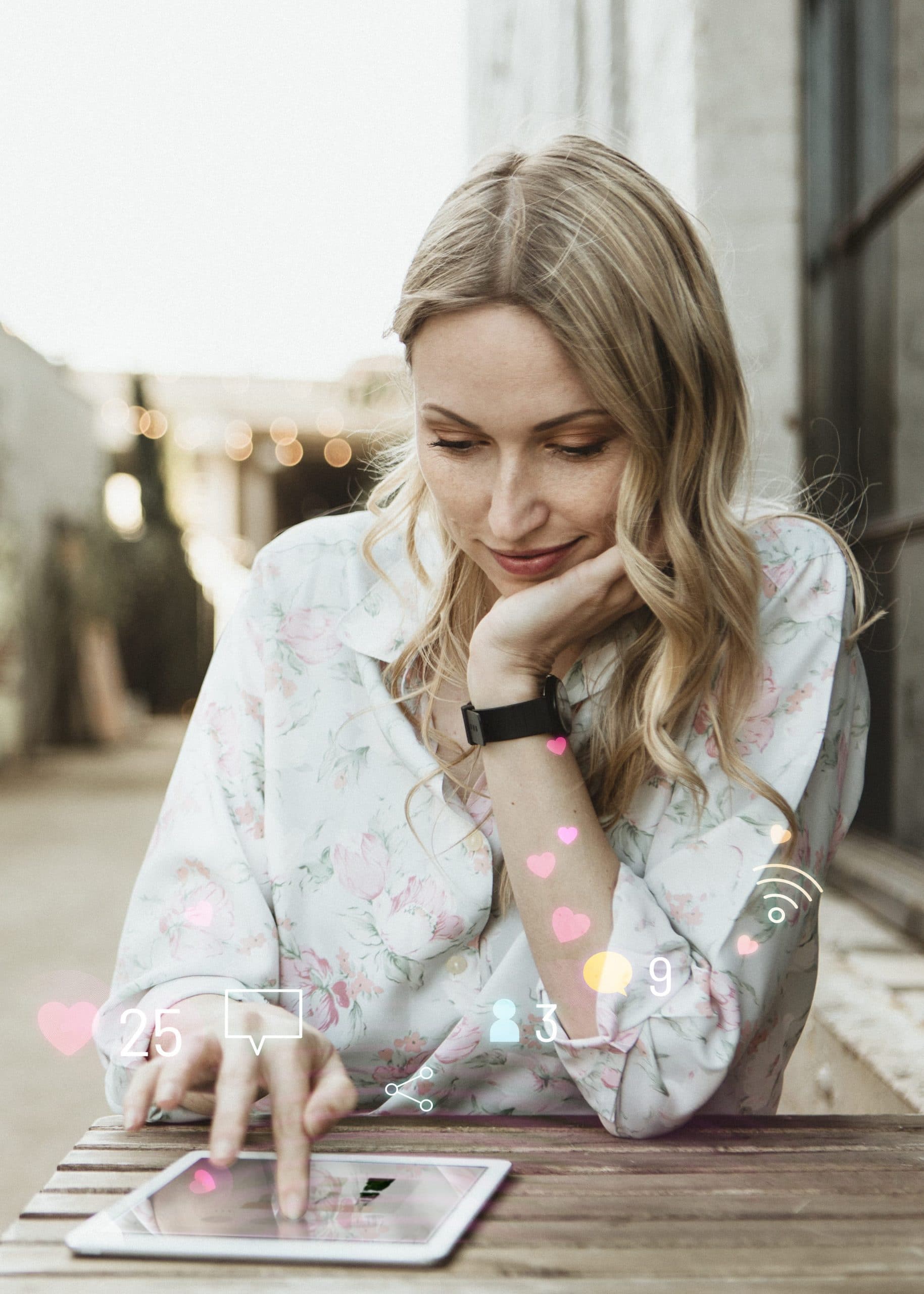 woman sitting outdoors at a picnic table looks at her tablet