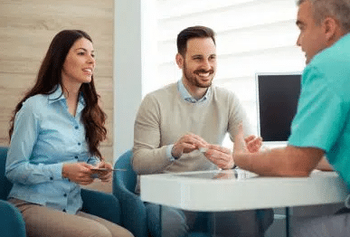 dentist consulting with two dental patients in his office