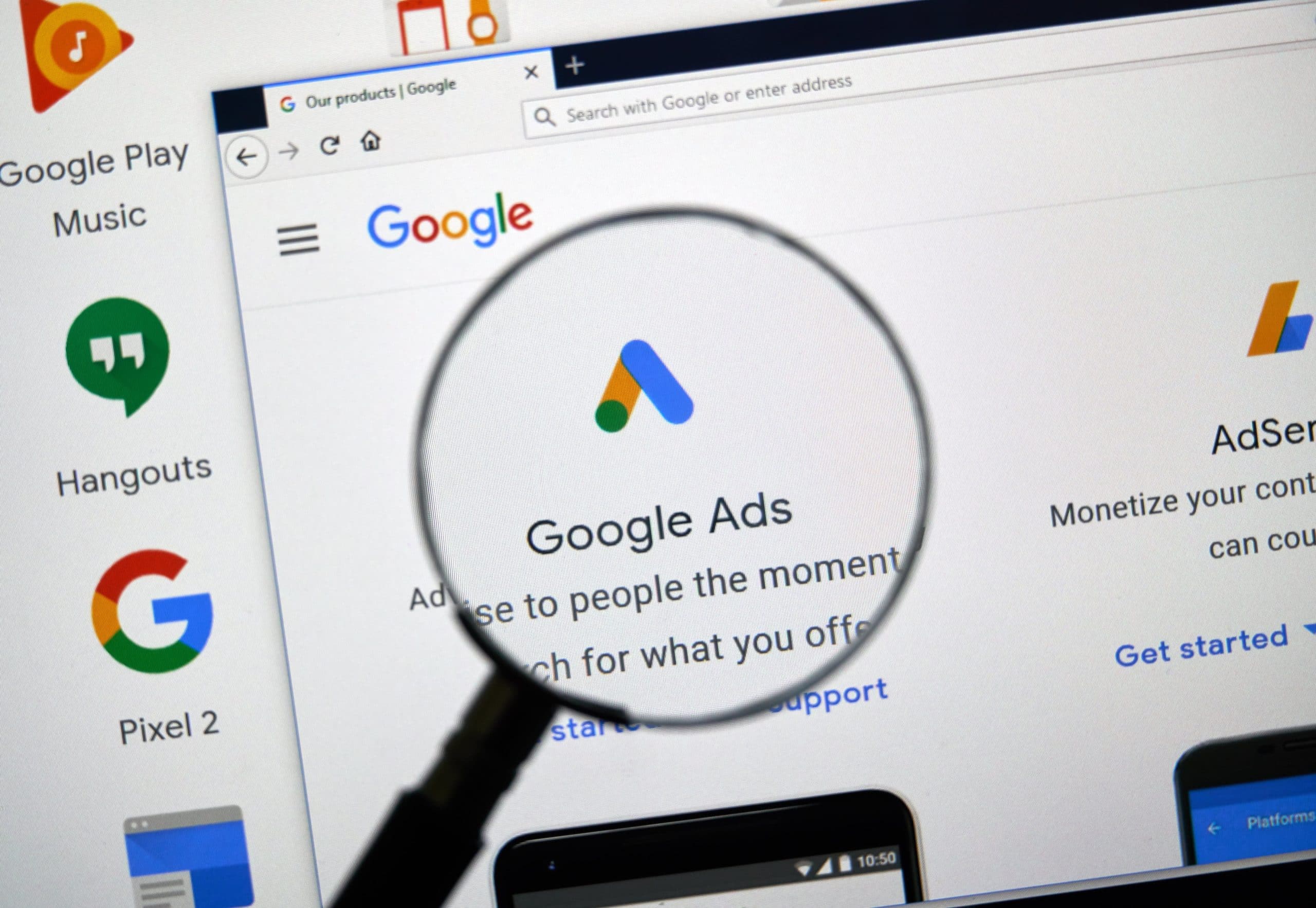 Magnifying glass focusing on the Google Ads homepage, highlighting digital advertising tools.