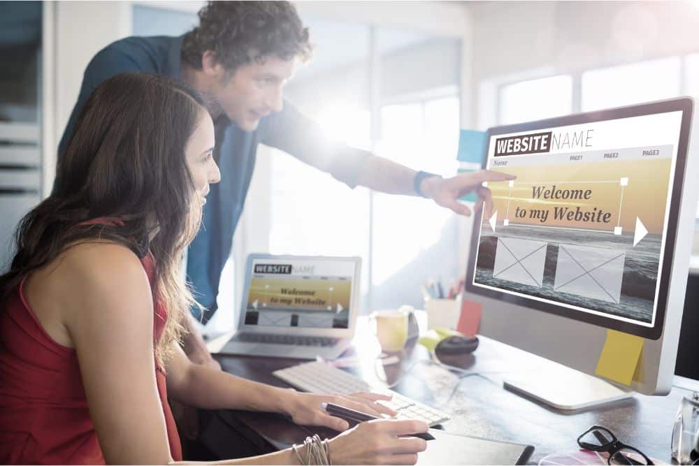 Two people collaborating on website design at a desktop computer.
