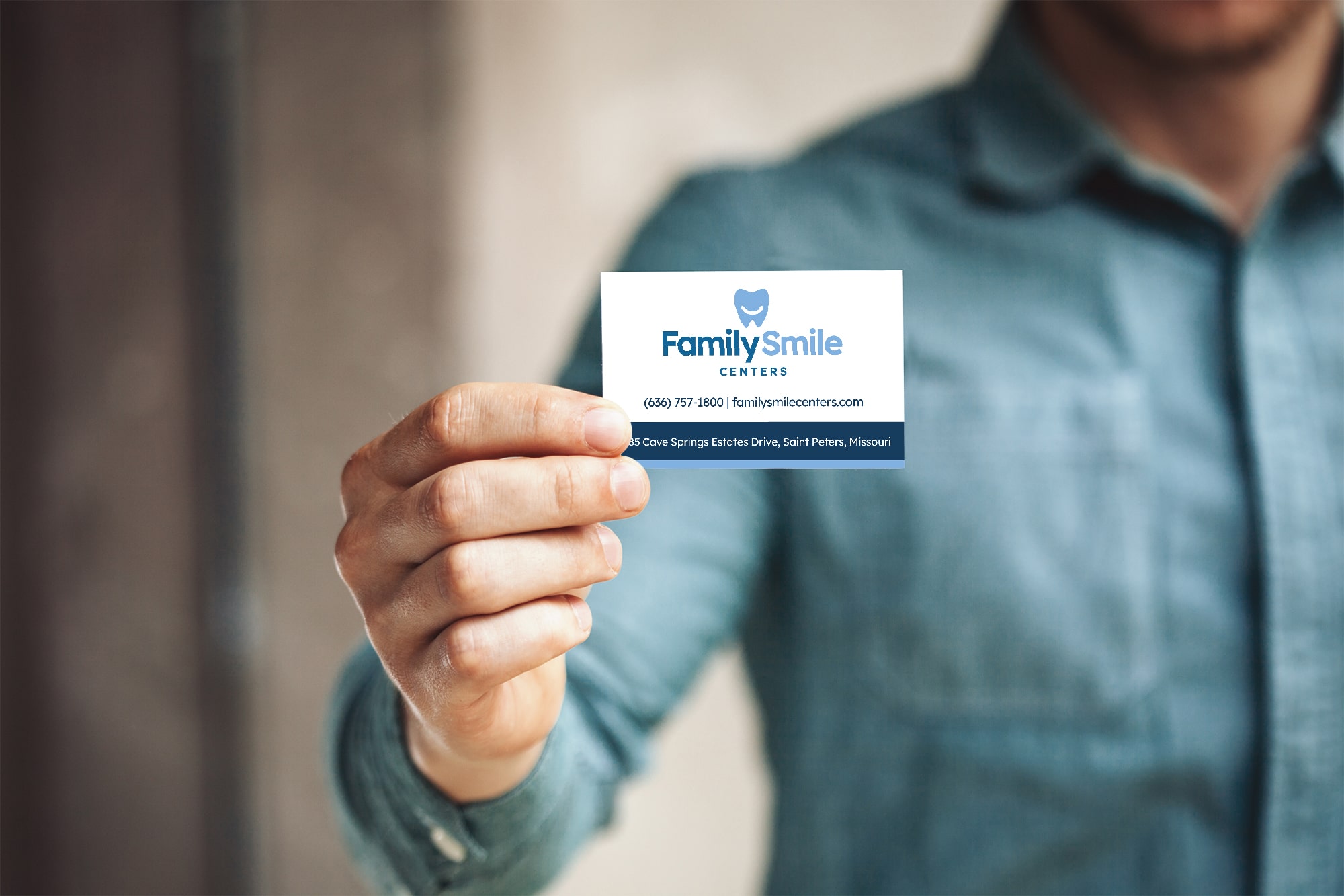 CollateralService-min Person holding a Family Smile Centers business card, highlighting dental clinic contact information.